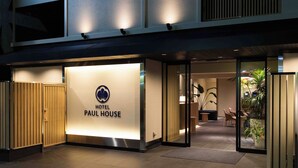 The exterior of the Paul House Hotel with a well-lit entrance, a reception area visible through glass doors, and a modern design with a tiled floor. - HOTEL PAUL HOUSE (Tokyo)