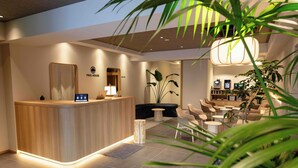 A modern reception area with a wooden counter, seating area, and indoor plants. - HOTEL PAUL HOUSE (Tokyo)