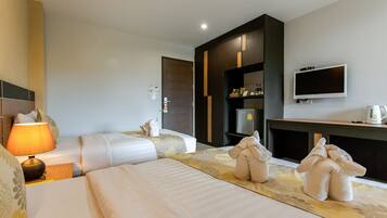 A hotel room with two beds, a TV, a minibar, and a lamp.