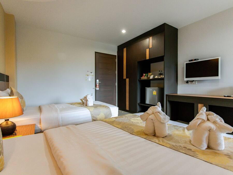 A hotel room with two beds, a TV, a minibar, and a lamp.