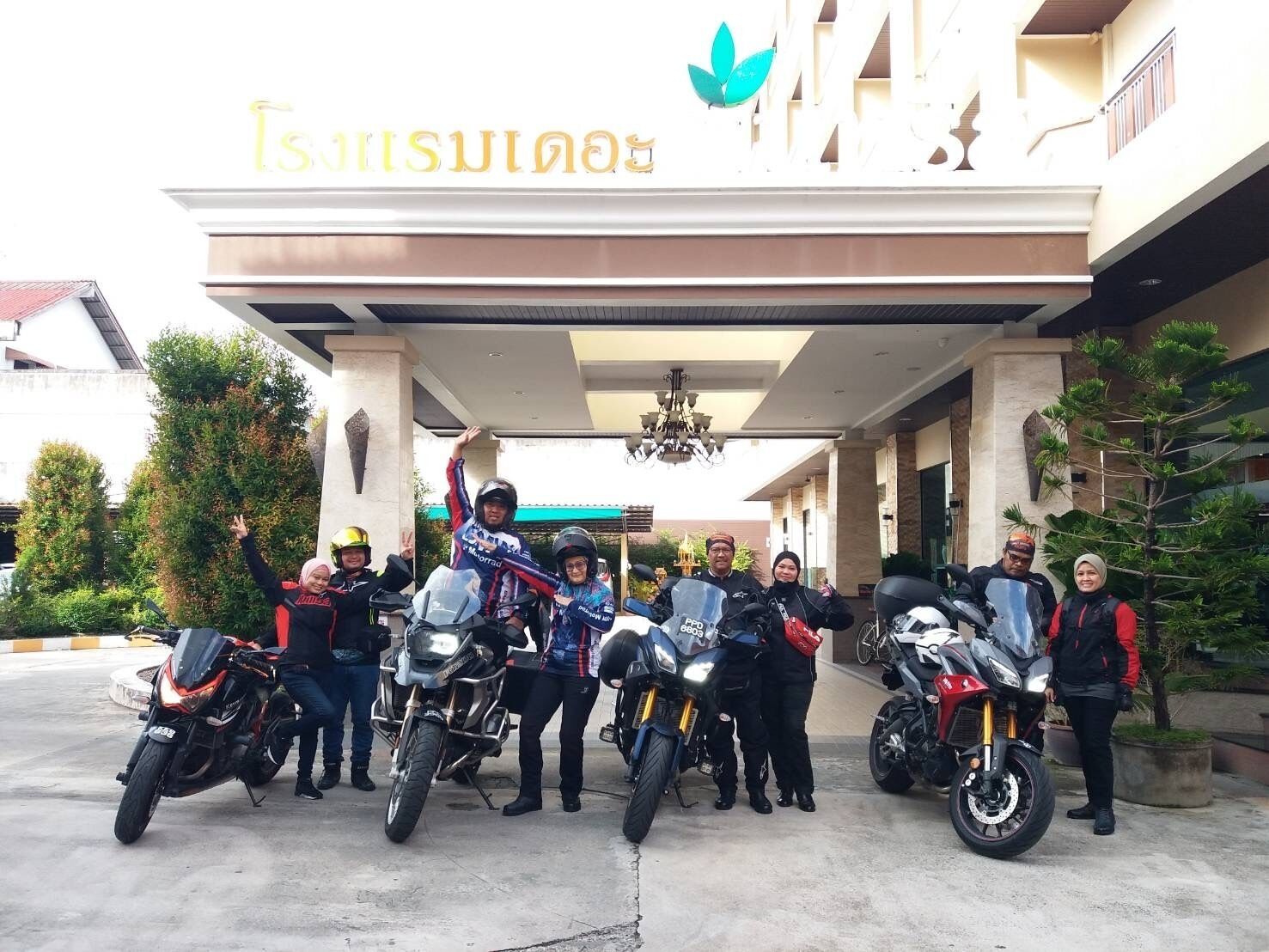 A group of people with motorcycles in front of a building with a sign that reads "TISANISULINAS".