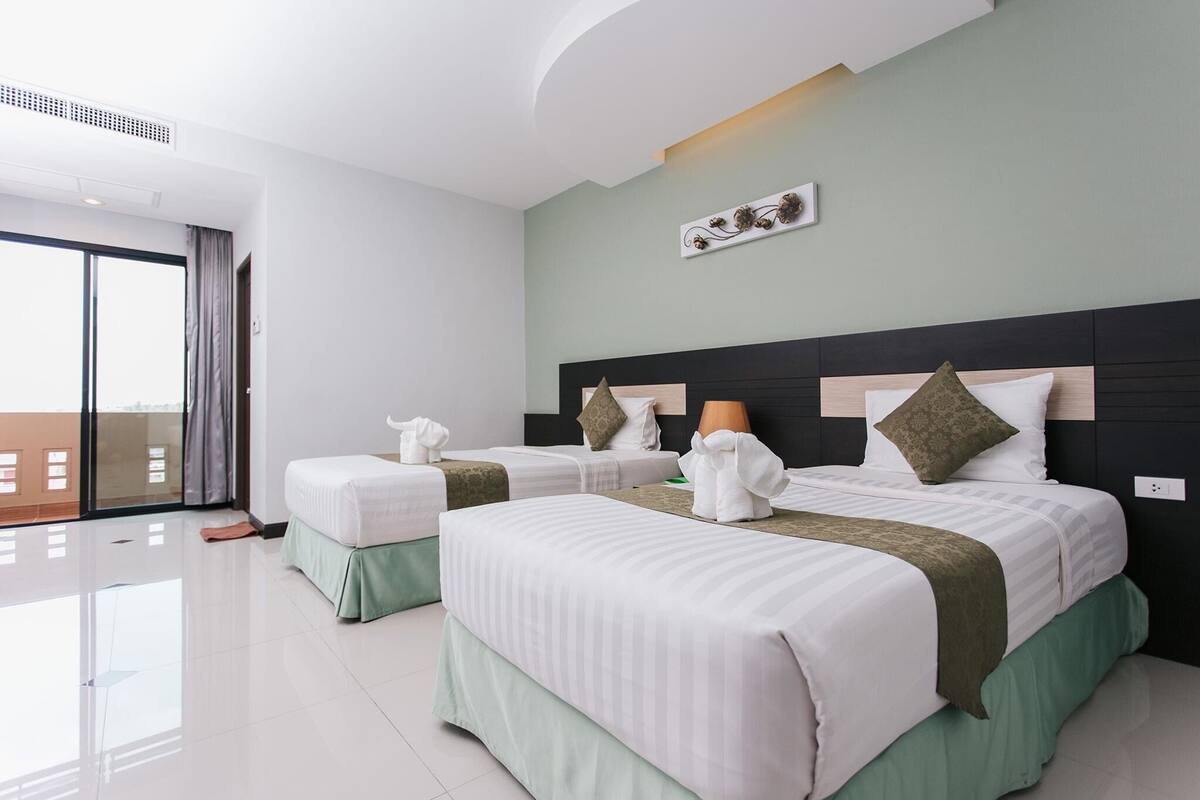 Habitación de hotel con dos camas, un ventanal grande y una lámpara en el techo.