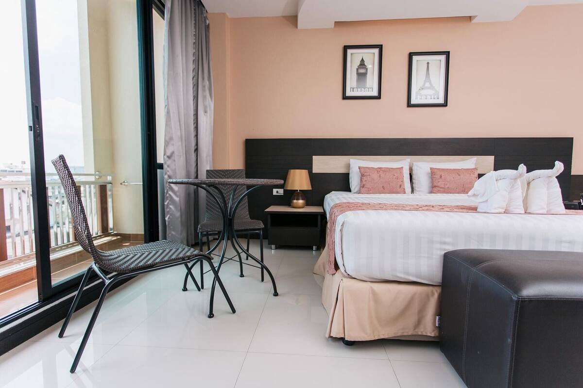 Una habitación de hotel con cama, una silla, una mesa y una mesita de noche.