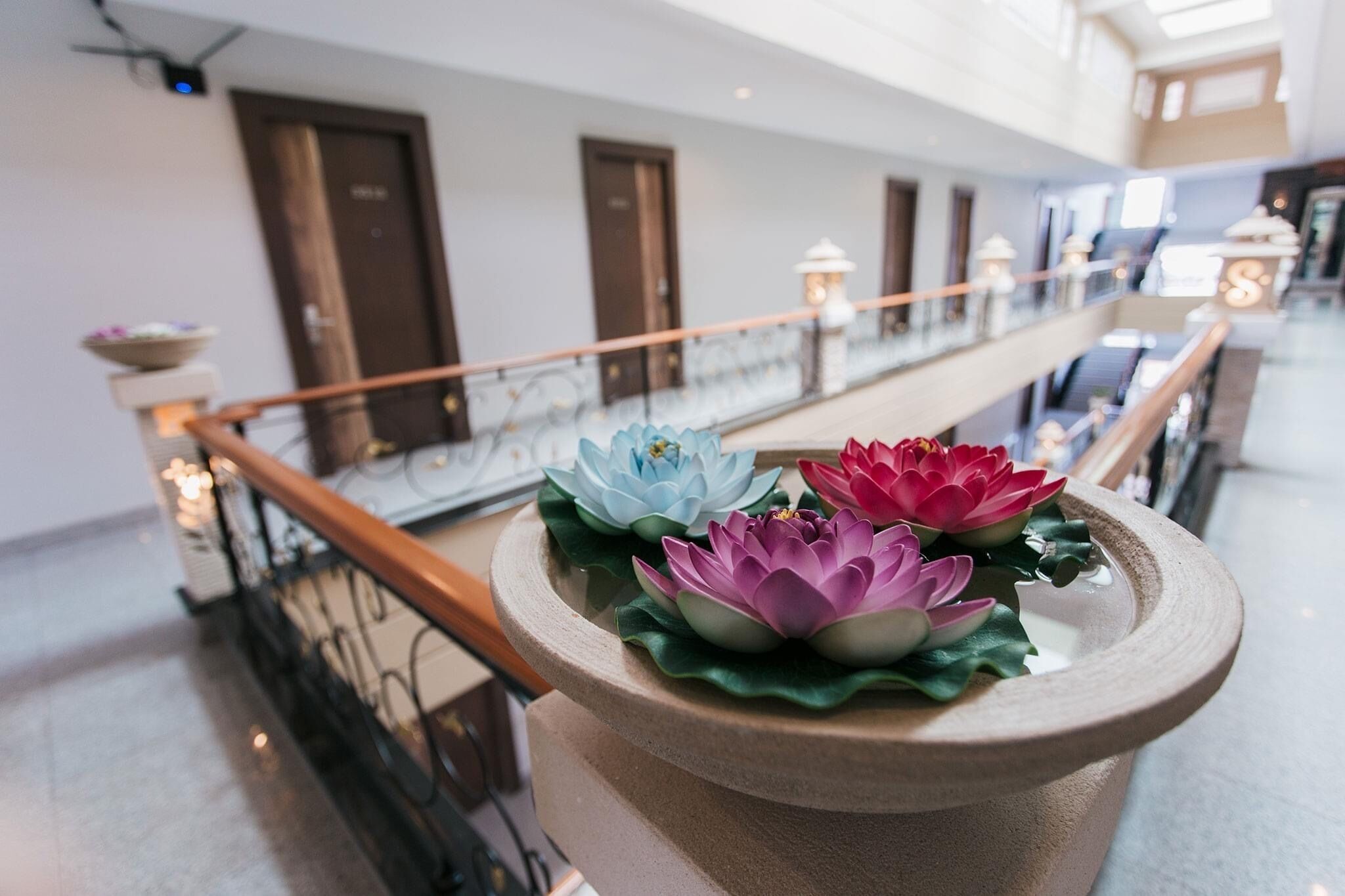 Un vaso in pietra con fiori di loto su un balcone.