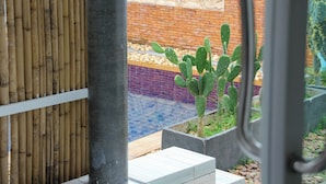Un jardin de cactus agrémenté d’un mur en bambou et d’un mur en briques orné de sculptures.