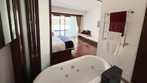 Une salle de bain moderne dotée d’une baignoire, d’un espace douche et d’une grande fenêtre donnant sur une piscine.