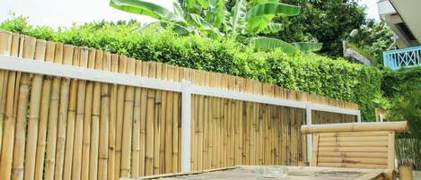 A bamboo fence, a table with a glass, and a chair.