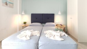 Ein Doppelbett mit dunklem Kopfteil, zwei Nachttische mit Lampen, eine kleine Topfpflanze und ein gewebter Korb auf der rechten Seite.