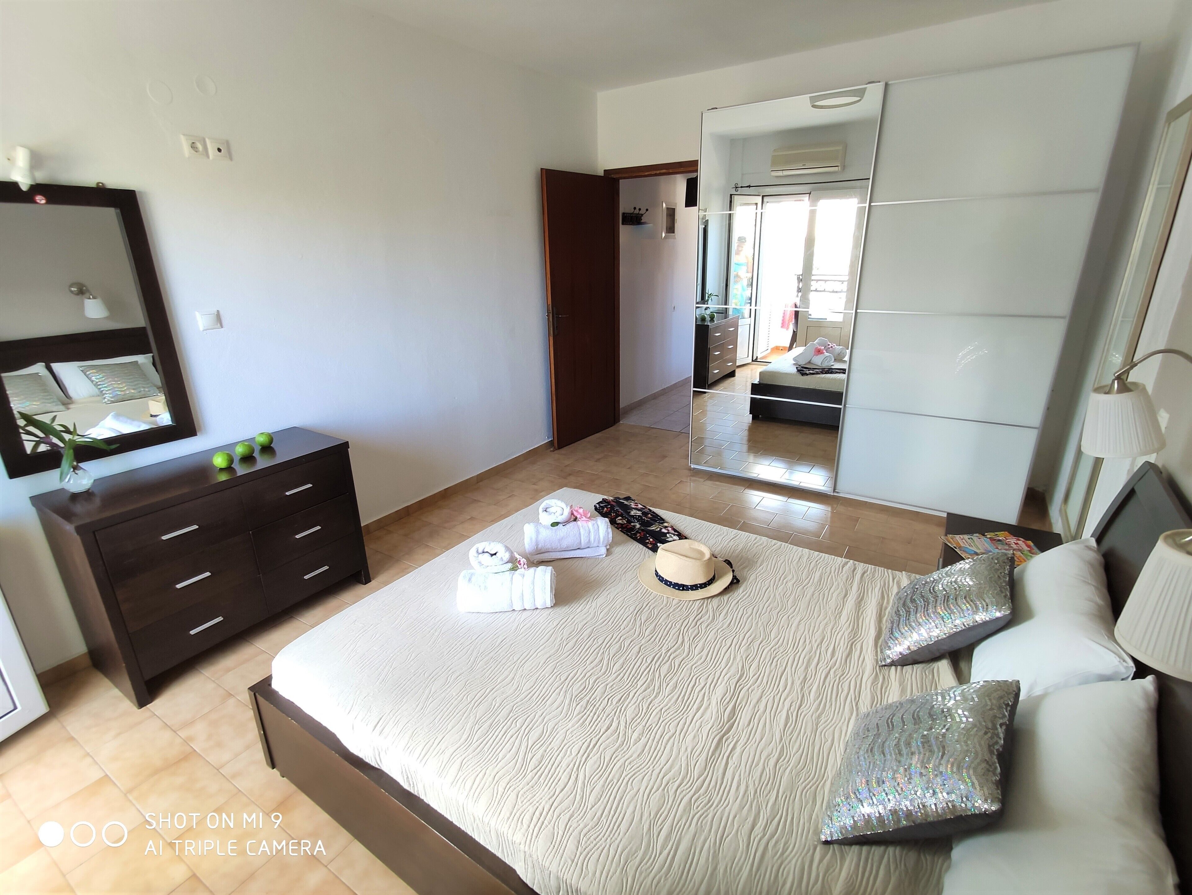 A bedroom with a bed, a dresser, a mirror, and a wardrobe.