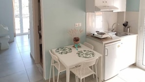 Eine moderne Küche mit weißen Schränken, einem Esstisch mit Stühlen und einem kleinen Kühlschrank.