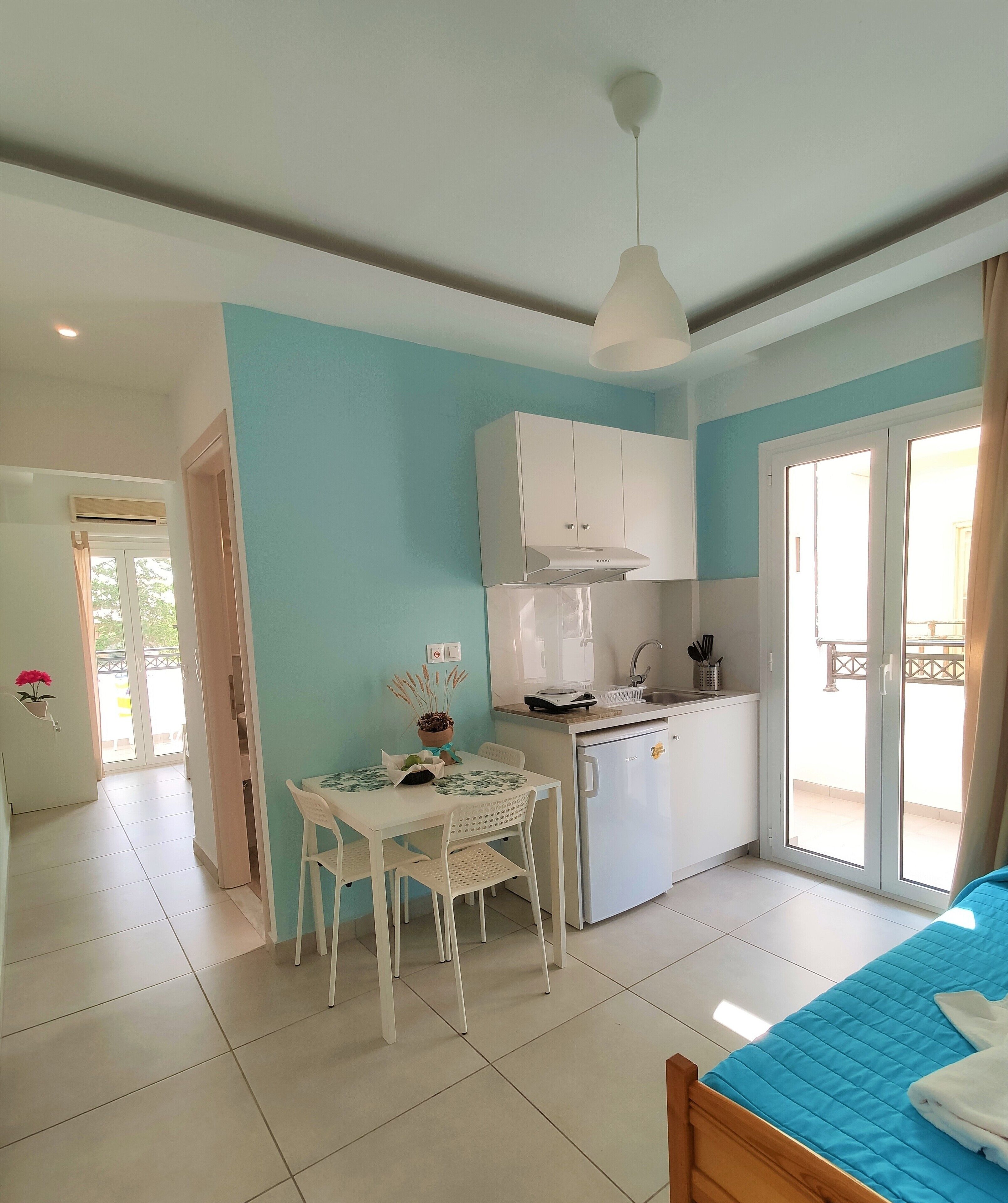 A compact kitchen with a dining area, a bed, and a sliding glass door to the outside.