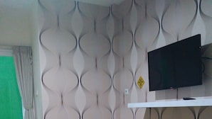 Ein Zimmer mit einem Bett, einem Fernseher auf einem Regal und einer Wand mit Muster.