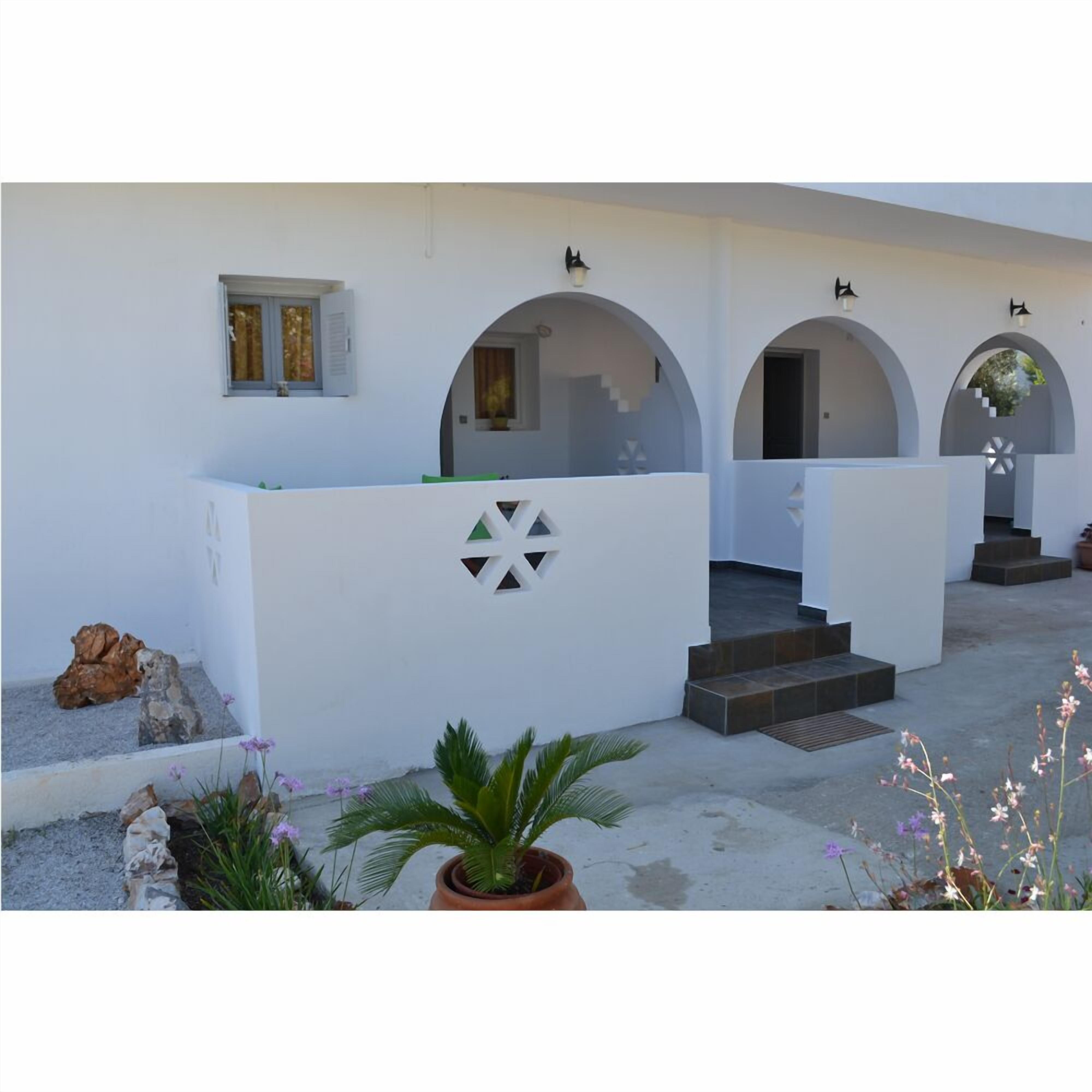 A white building with arched doorways and a central staircase leading to an upper level.