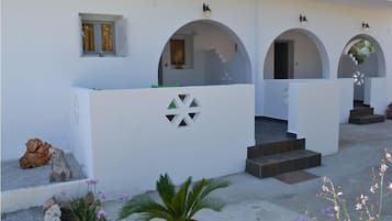 A white building with arched doorways and a central staircase leading to an upper level.