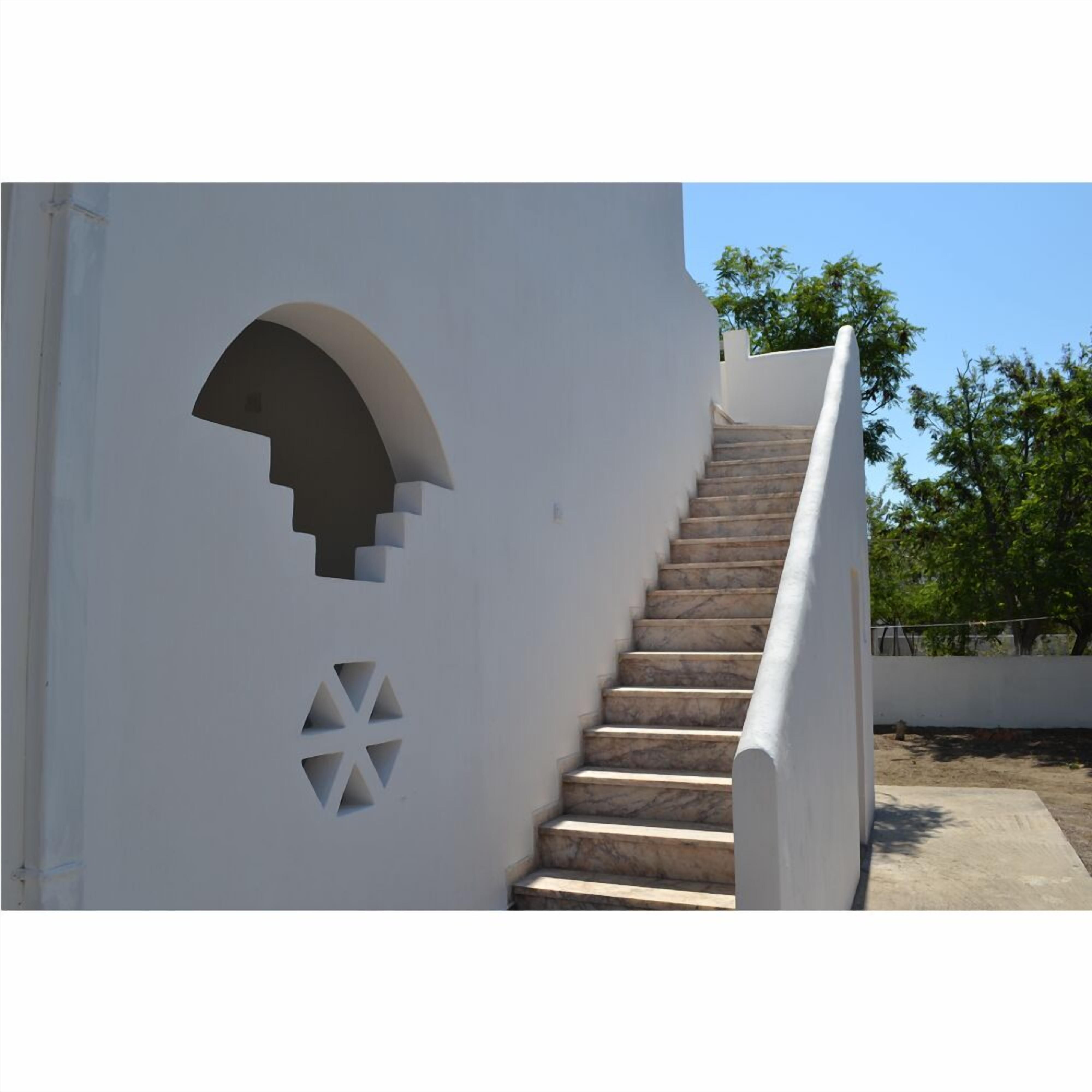 Una escalera con un muro blanco decorado con recortes geométricos.
