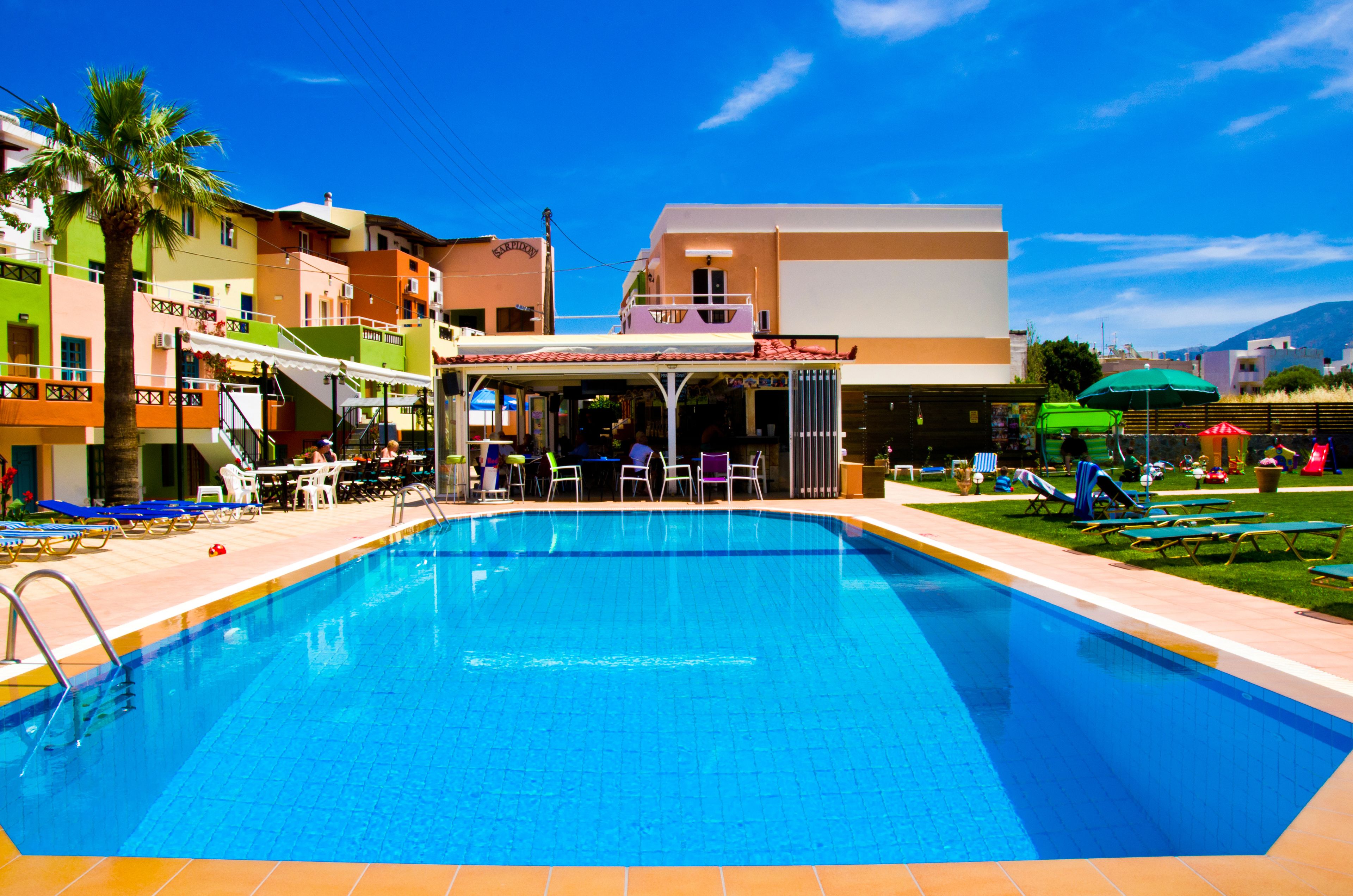 A swimming pool with lounge chairs and a covered seating area.