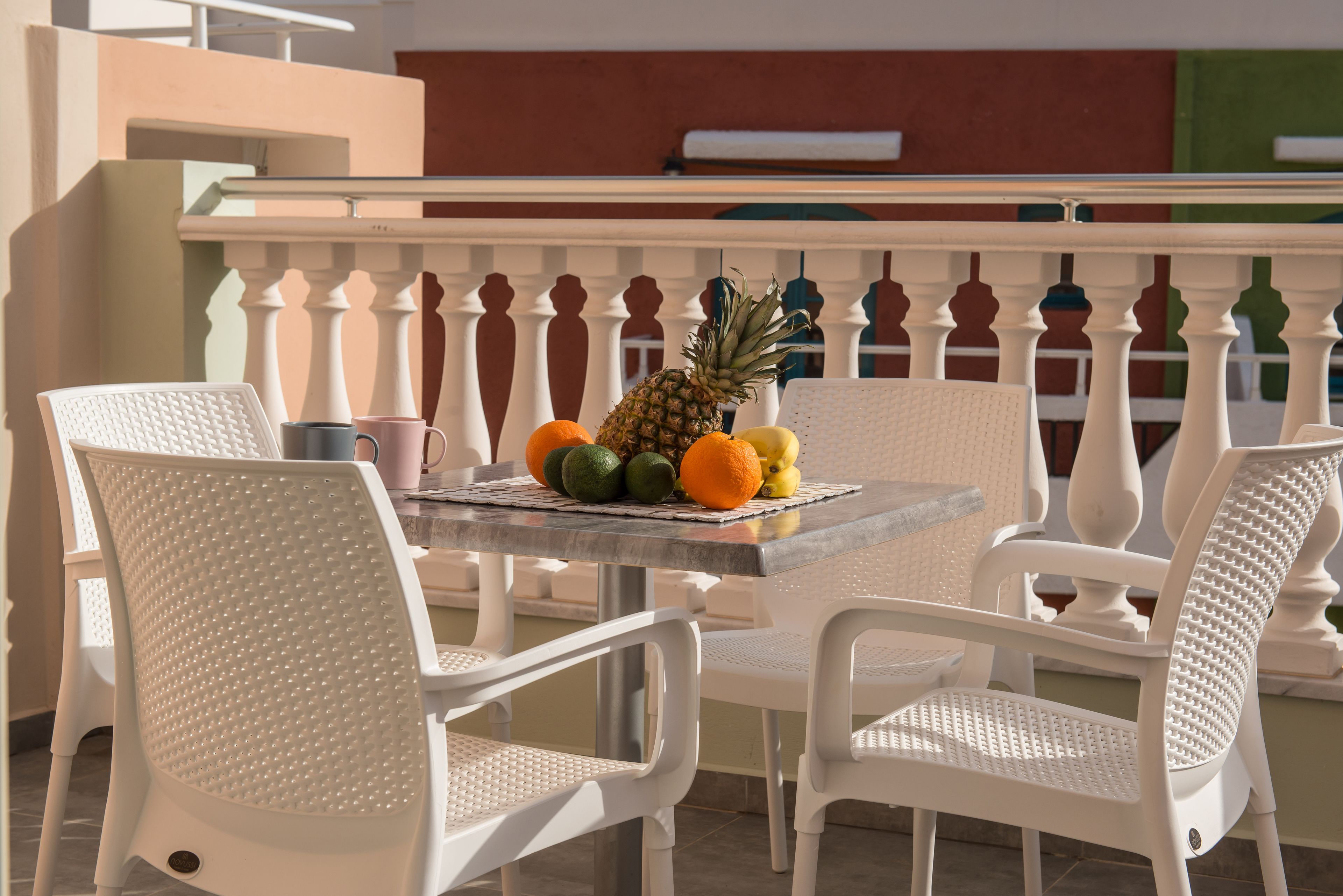 A table with chairs and a fruit arrangement.