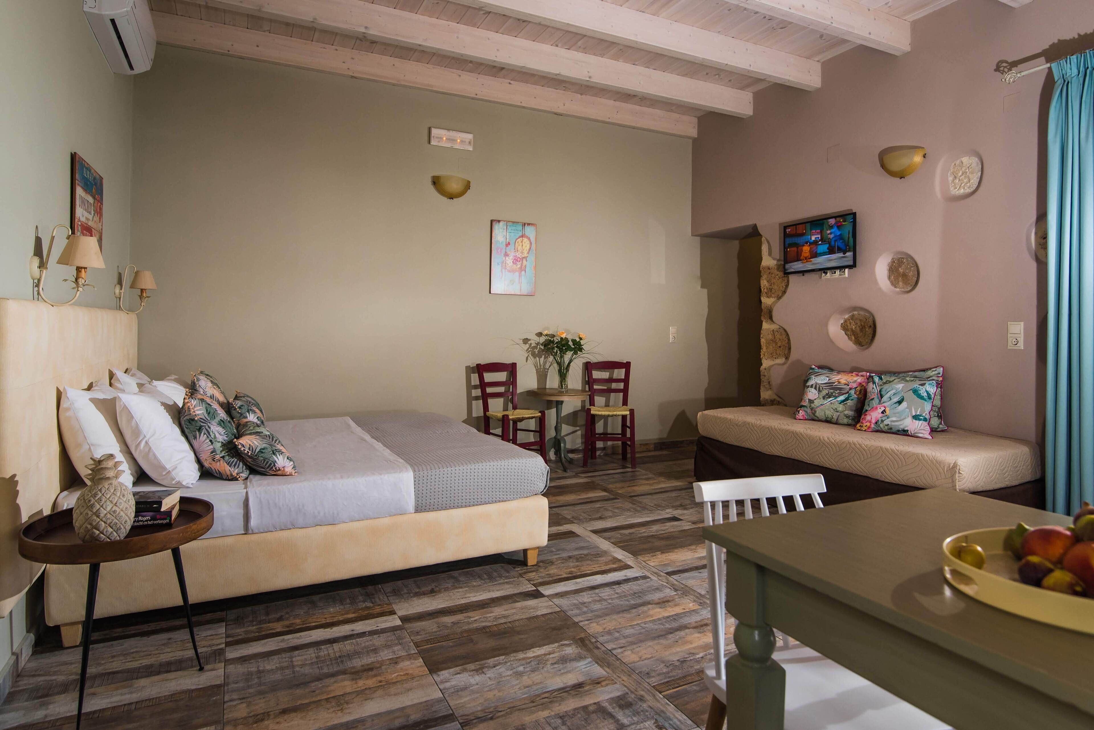 A cozy room with a bed, a sofa, a dining table, and a TV.