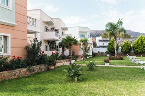 Un edificio residencial con balcones, un césped bien cuidado y montañas al fondo.
