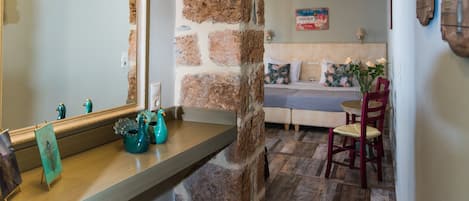 Un baño con pared de piedra, un espejo y un tocador de madera.