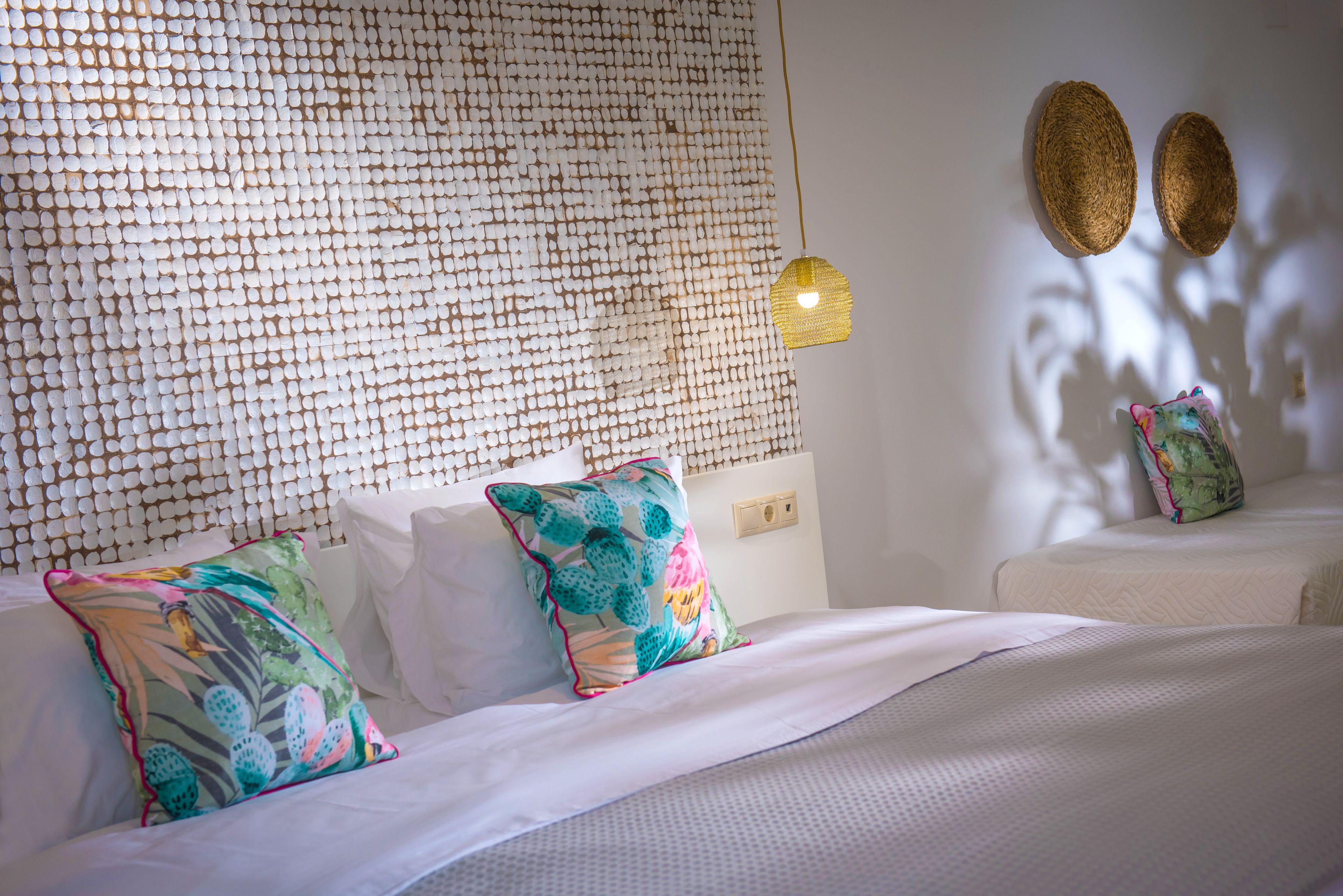 Ein Hotelzimmer mit einer Wand mit Muster, einem Bett mit weißer Bettwäsche und zwei dekorativen Wandleuchten.