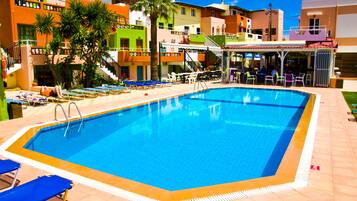 Una piscina con sillas de descanso y una zona de bar.