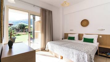 Habitación de hotel con cama, escritorio, vista por una puerta de vidrio y una lámpara en el techo.
