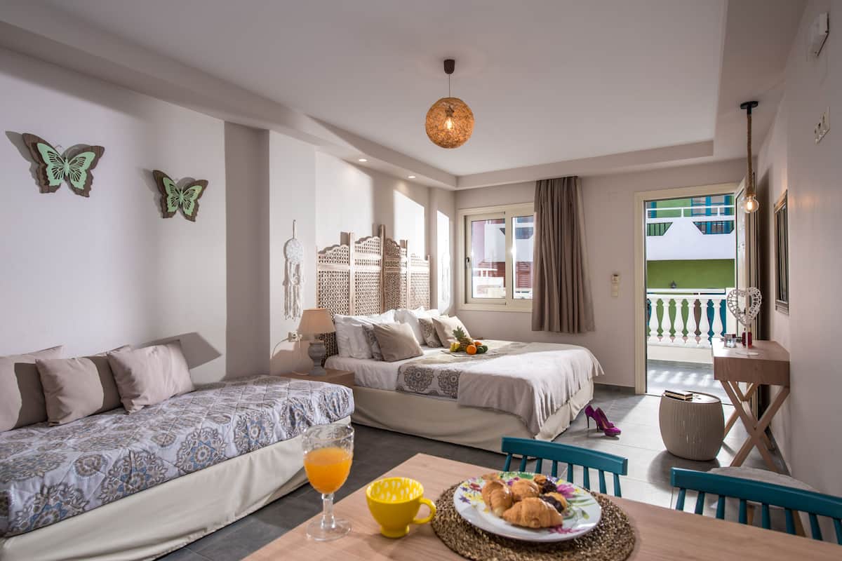 A hotel room with two beds, a dining table with breakfast, and a balcony with a view.