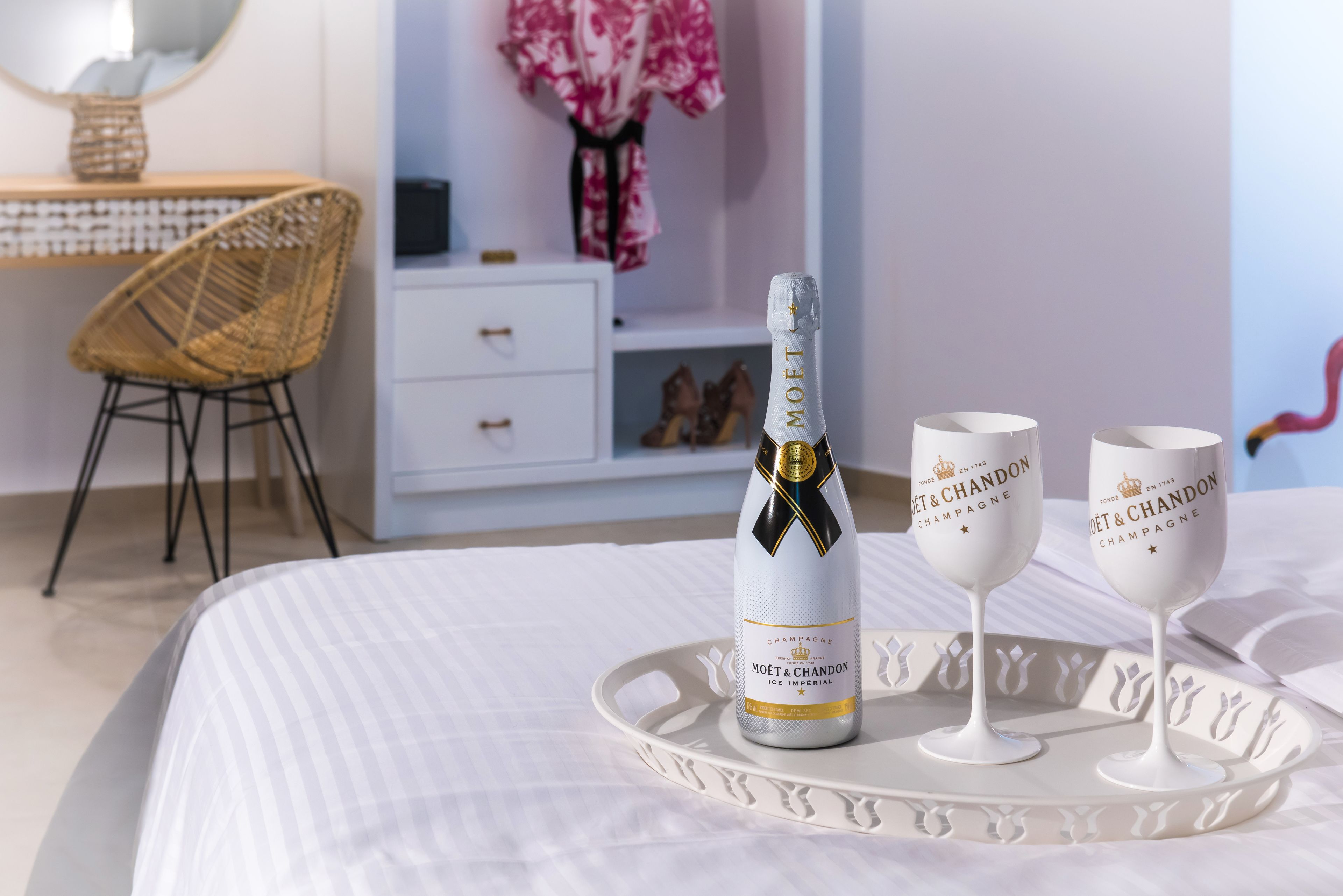 Ein Bett mit weißer Bettdecke, eine Champagnerflasche und zwei Gläser auf einem Tablett.