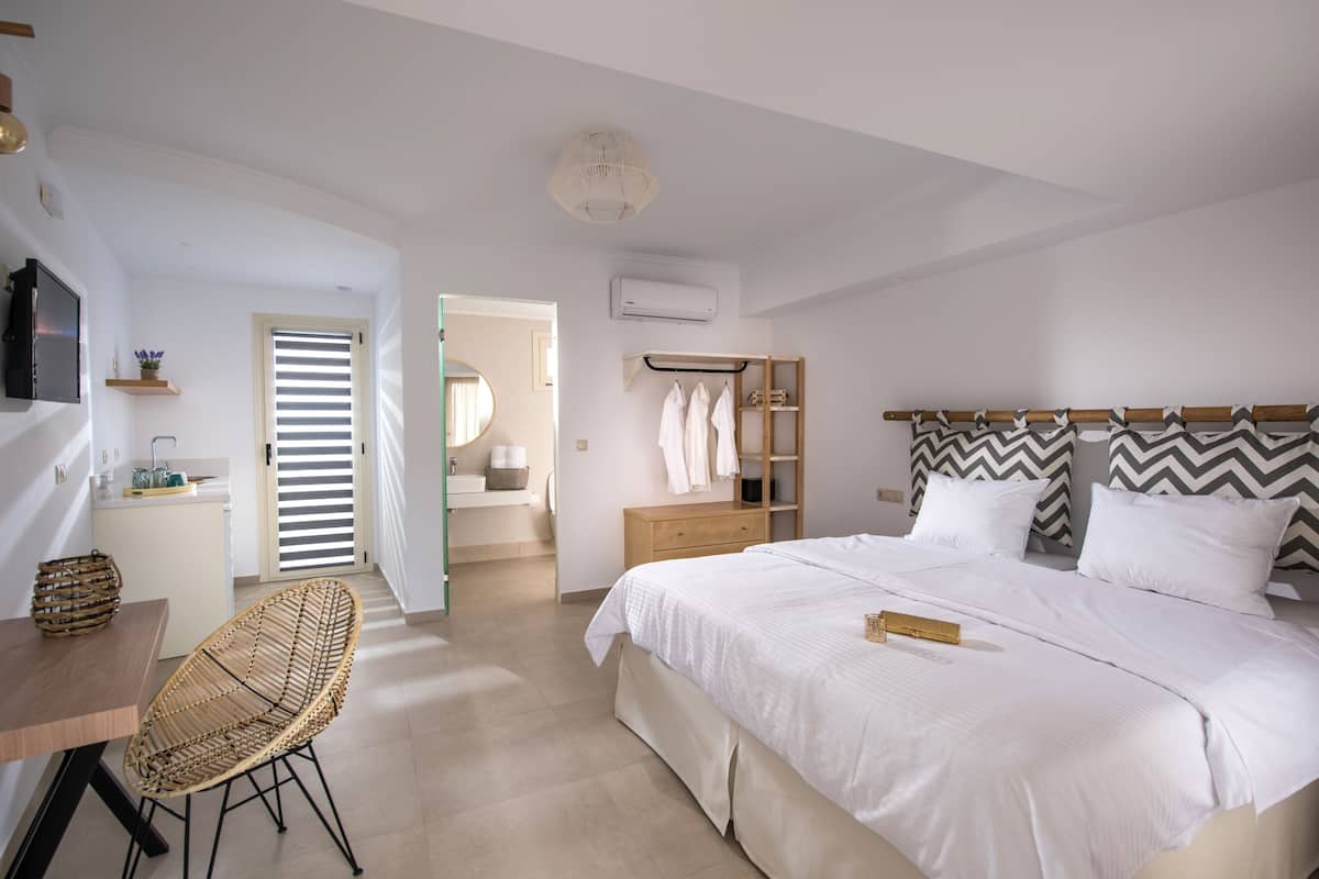 A bedroom with a bed, bedside table, chair, wardrobe, and a bathroom visible through an open door.