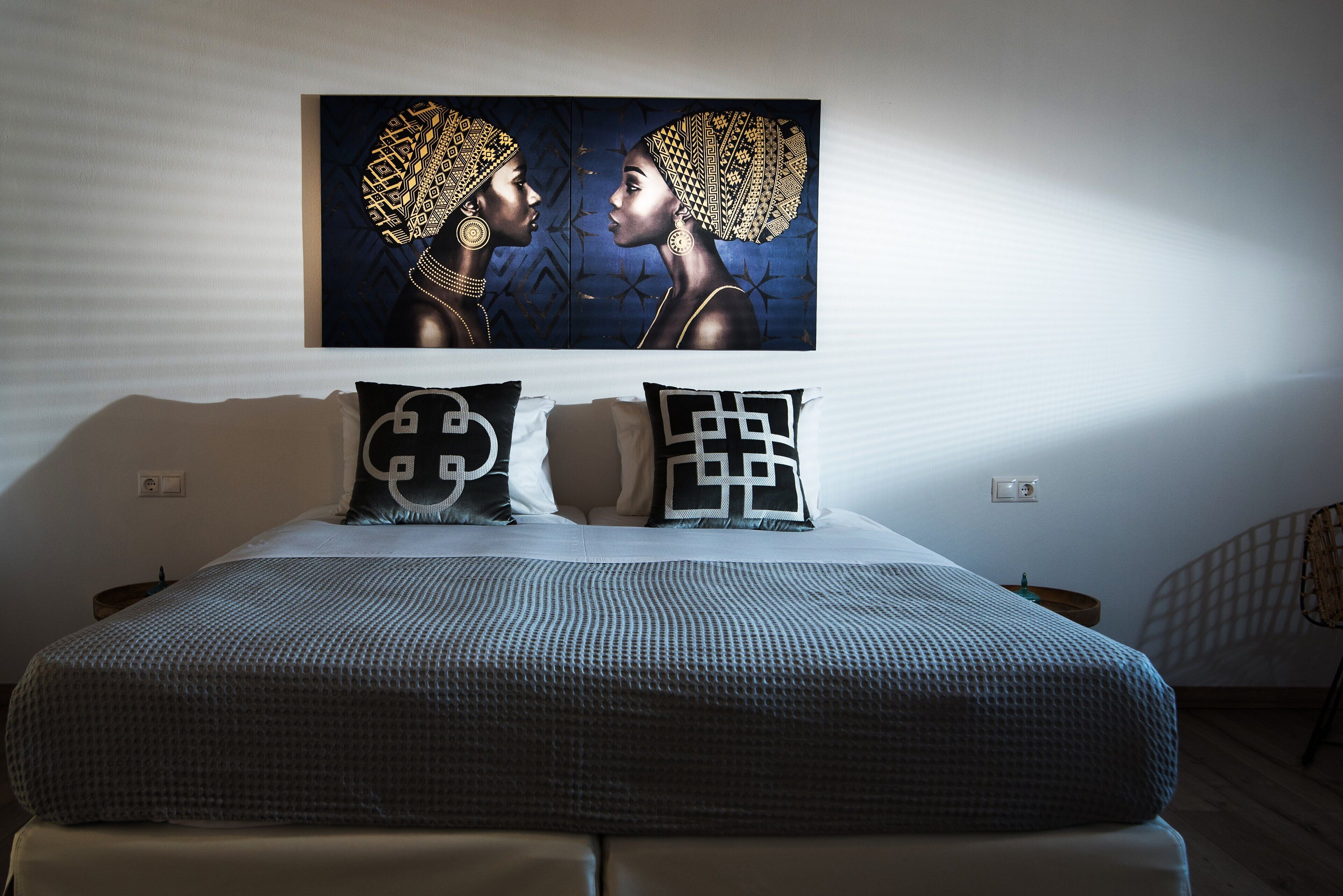 A neatly made bed with a patterned bedspread and two pillows with geometric designs.