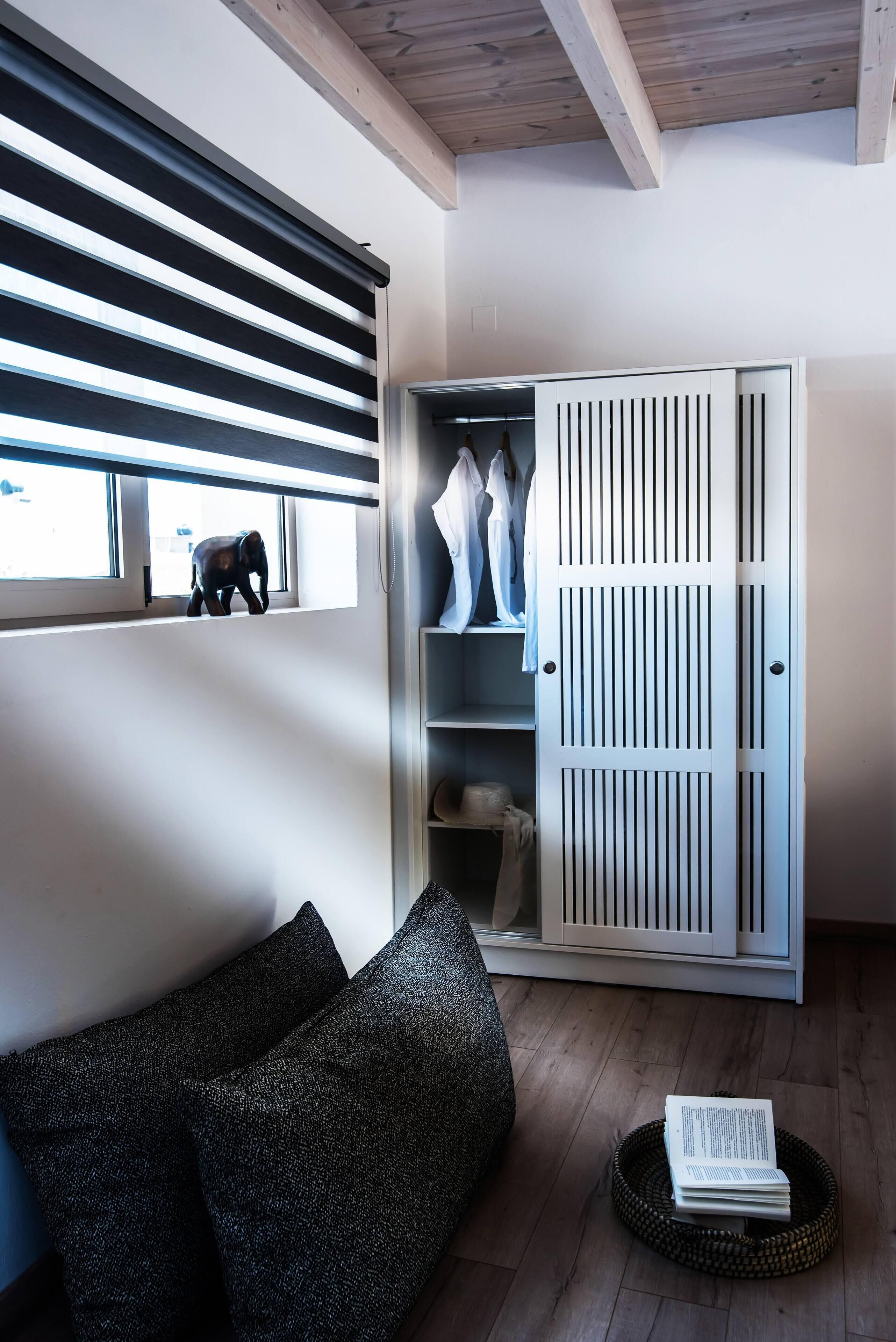 Une chambre moderne dotée d’une grande fenêtre, d’une armoire intégrée et d’un coin salon confortable.