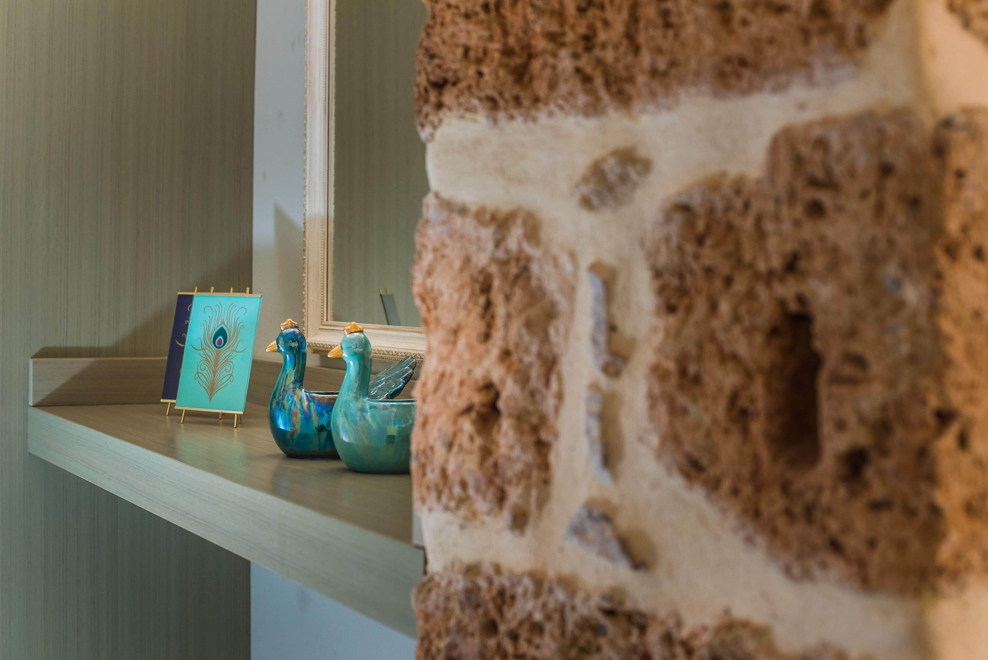 A wooden shelf with a teal decorative piece and a blue ceramic duck.