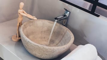 Un bagno con un lavabo di pietra, un manichino di legno e un asciugamano.