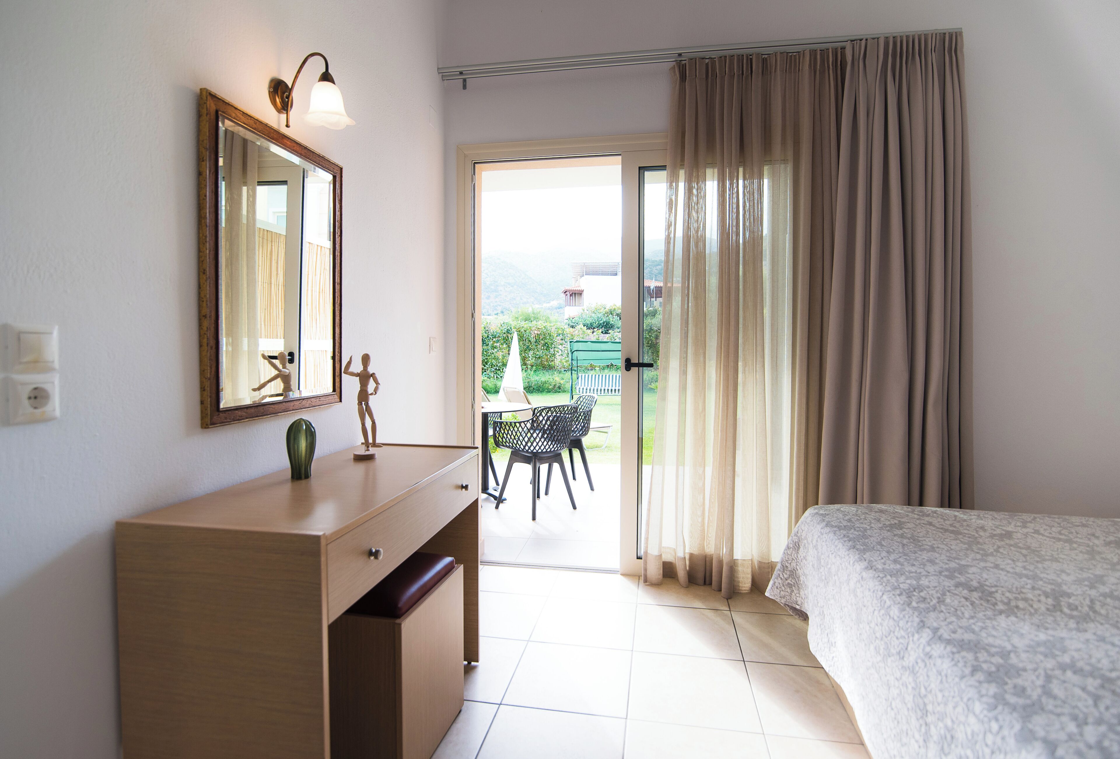 A bedroom with a bed, a dresser, a mirror, and a view of an outdoor patio.