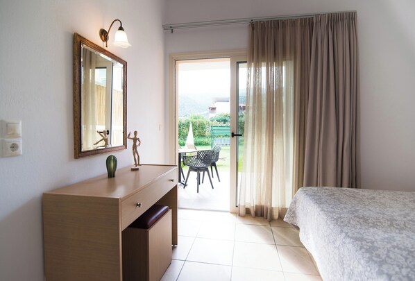 A bedroom with a bed, a dresser, a mirror, and a view of an outdoor patio.