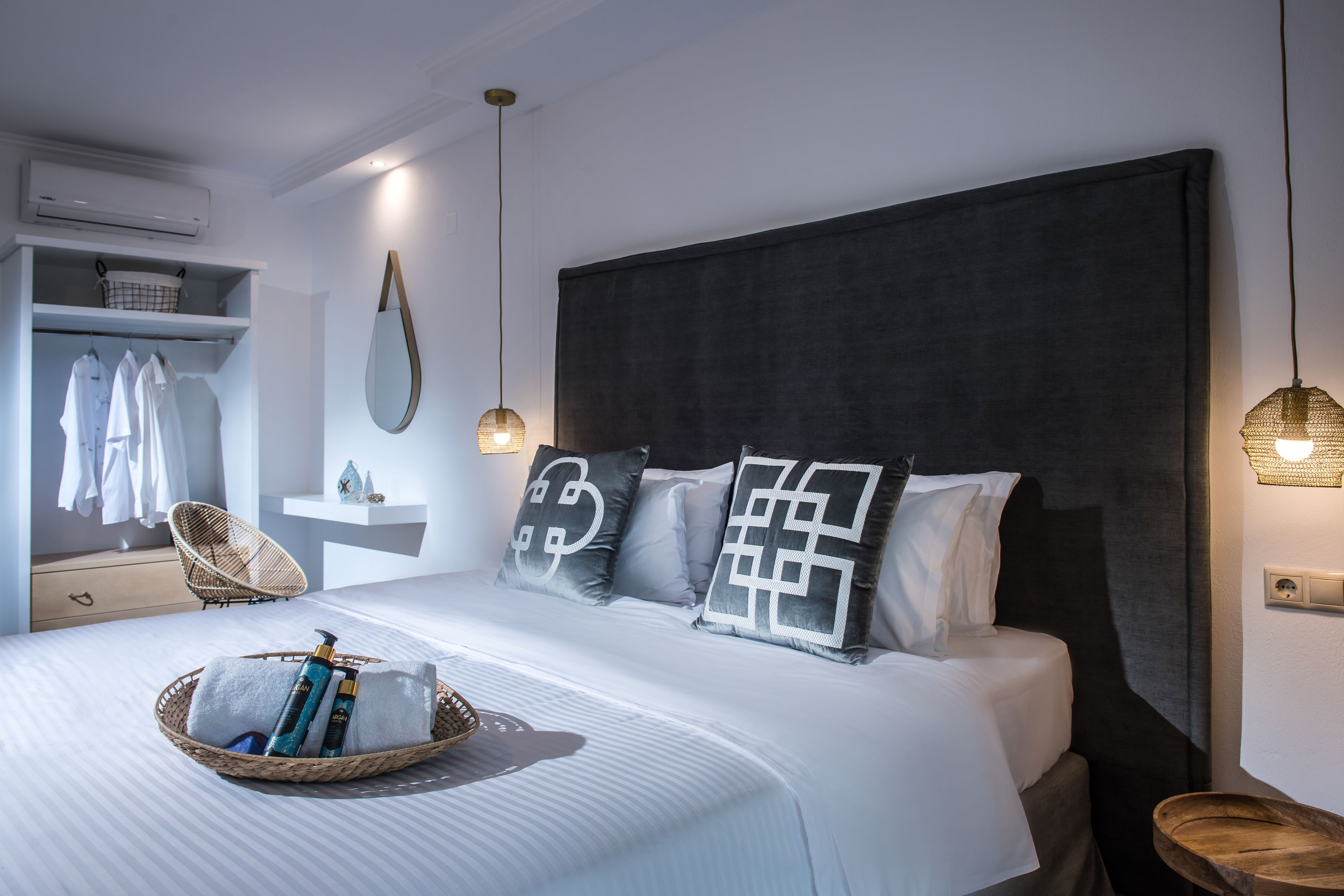 Une chambre à coucher bien aménagée, avec un grand lit, une table de chevet, un luminaire suspendu et un climatiseur fixé au mur.