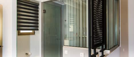A modern bathroom with a glass shower enclosure, a toilet, and a sink with a towel.