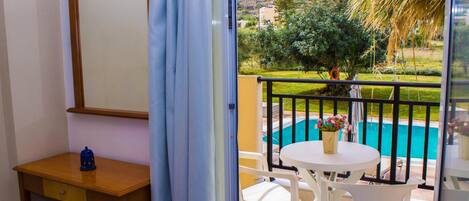 A balcony with a pool view, a wooden desk, and a table with chairs.