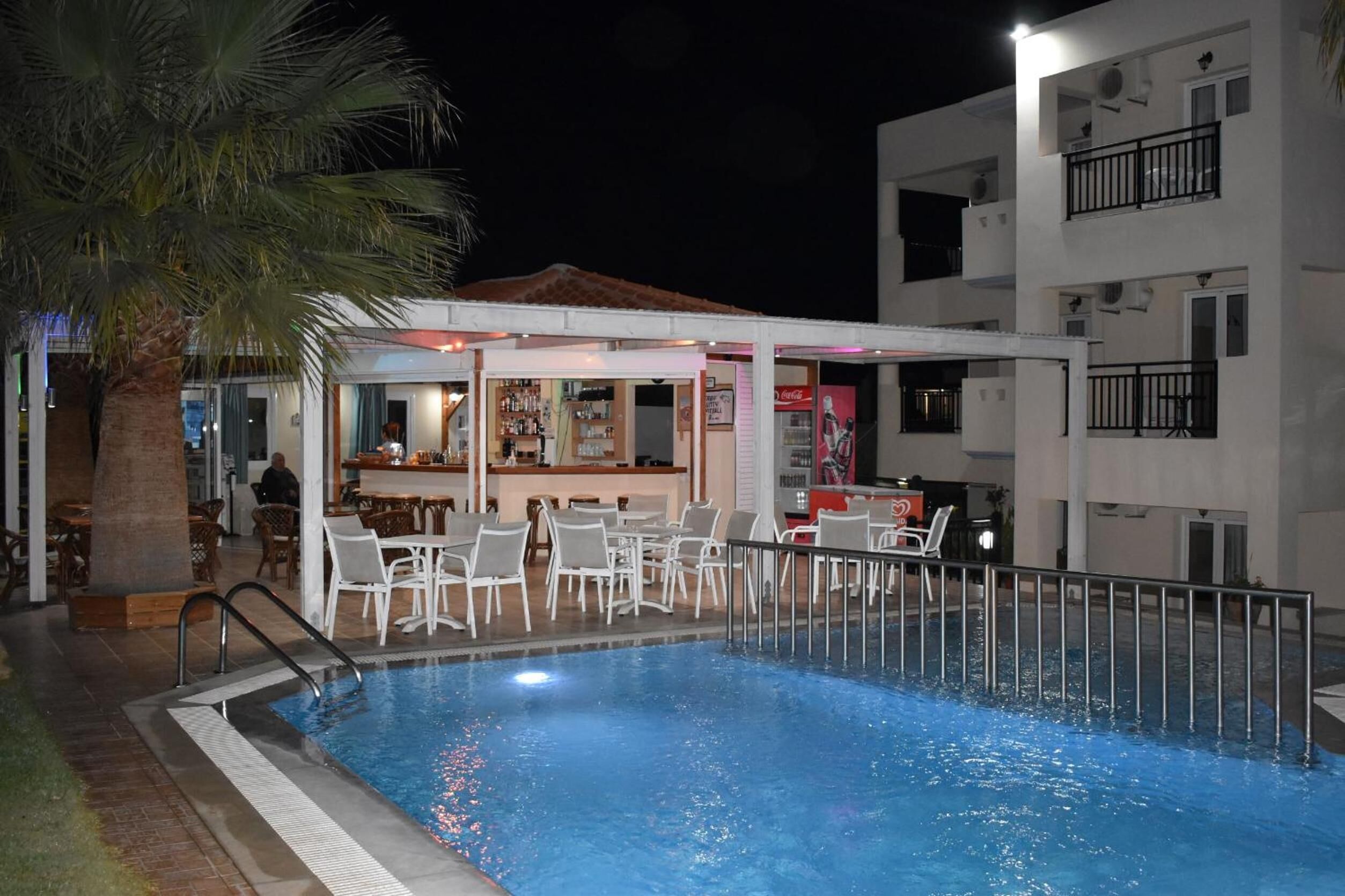 A swimming pool with lounge chairs and a bar area, surrounded by a building with balconies.