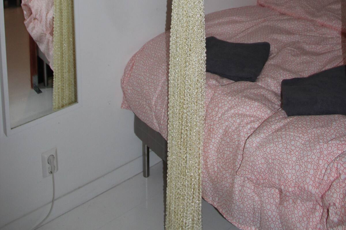 A bedroom with a four-poster bed, a mirror, and a shelf with toiletries.