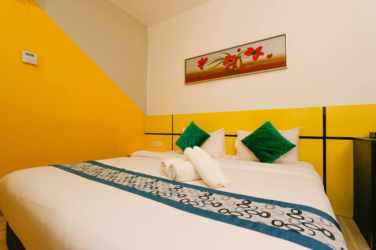 A hotel room with a bed, a painting on the wall, and a yellow and white color scheme.