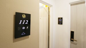 A hallway with a digital sign displaying room number 112, a door with a keypad, and a doorbell button. - Golden Roof Hotel Sunway Ipoh (Ipoh)