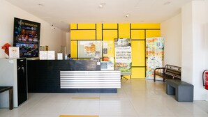 A reception desk with a black and white design, a yellow wall with framed pictures, and a bench to the right. - Golden Roof Hotel Sunway Ipoh (Ipoh)