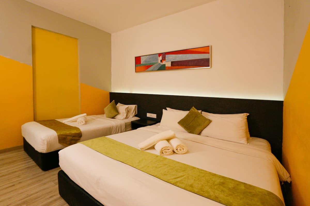 A hotel room with two beds, a green bed runner, and a painting on the wall.