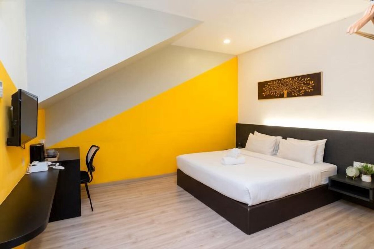 Un dormitorio con cama, mesita de noche y escritorio con silla.