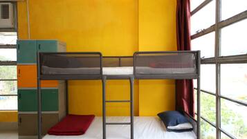 A bunk bed room with a yellow wall, a window with a view, and storage cabinets.