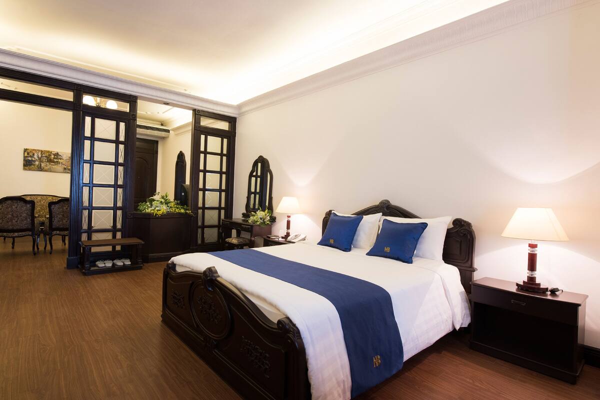 A hotel room with a large bed, bedside tables, a desk, and a chair.