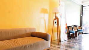 Ein Zimmer mit einer Couch, einer Lampe und zwei Sesseln.