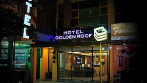 Ein Hotel namens 'Hotel Golden Roof' mit einer auffälligen Neonreklame, einem gut erkennbaren Eingang und einem Schild für 'Restoran Farhan' daneben.